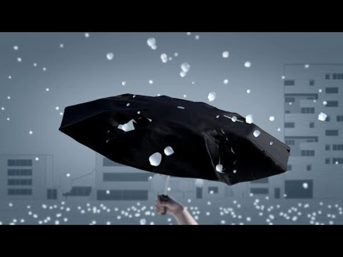 Eine Hand hält einen beschädigten schwarzen Regenschirm voller Löcher, während weiße Hagelkörner vor dem Hintergrund einer Stadtlandschaft mit Gebäuden und einem grauen Himmel fallen.