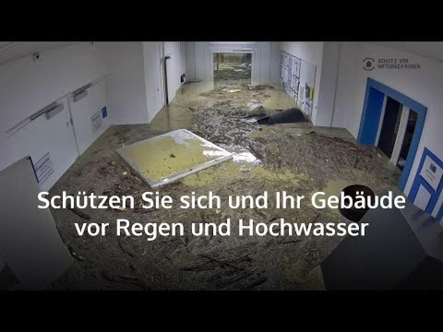 Ein überfluteter Flur in einem Gebäude mit Schutt und schlammigem Wasser auf dem Boden. Der Text auf Deutsch lautet: Schützen Sie sich und Ihr Gebäude vor Regen und Hochwasser.